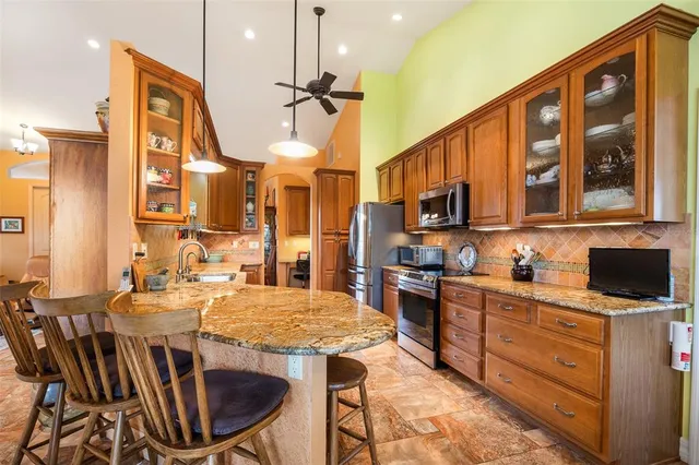 a kitchen with stainless steel appliances kitchen island granite countertop a stove top oven a sink a dining table and chairs