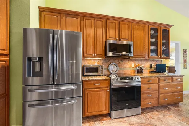 a kitchen with stainless steel appliances granite countertop a refrigerator and a stove top oven