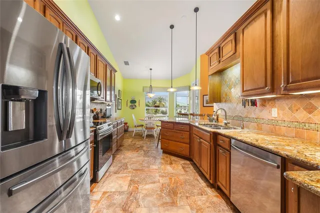 a kitchen with stainless steel appliances granite countertop a sink a stove and a refrigerator