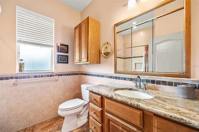 a bathroom with a granite countertop sink toilet and a mirror