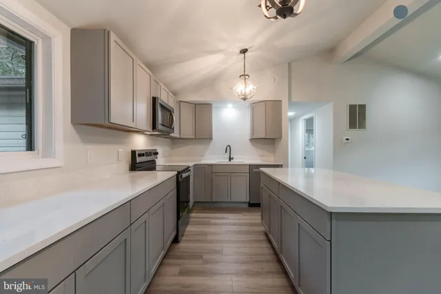 a large kitchen with a center island wooden floor stainless steel appliances and a window