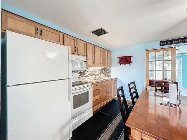 a kitchen with a refrigerator a stove a dining table and chairs with wooden floor