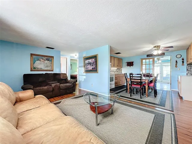 a living room with furniture and a dining table with wooden floor