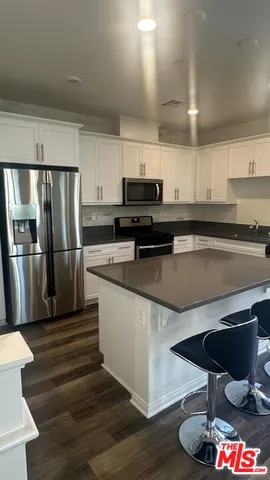 a kitchen with stainless steel appliances a refrigerator a stove a sink cabinets and wooden floor