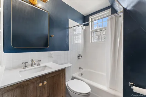 a bathroom with a bathtub shower sink vanity mirror and toilet