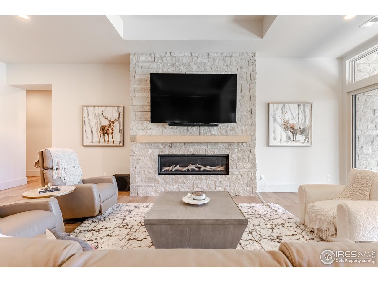 7572 Raphael Lane Littleton, CO 80125 - Photo 29 of 50 The media lounge is anchored by a stunning floor-to-ceiling linear fireplace wrapped in flagstone, mirroring the home's exterior materials and reinforcing the intentional architectural connection between indoors and out.