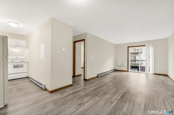 an empty room with wooden floor bathroom and windows