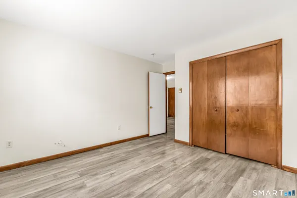 a view of an empty room with wooden floor and closet