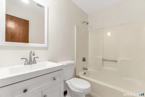a bathroom with a toilet a sink a mirror a bathtub and vanity