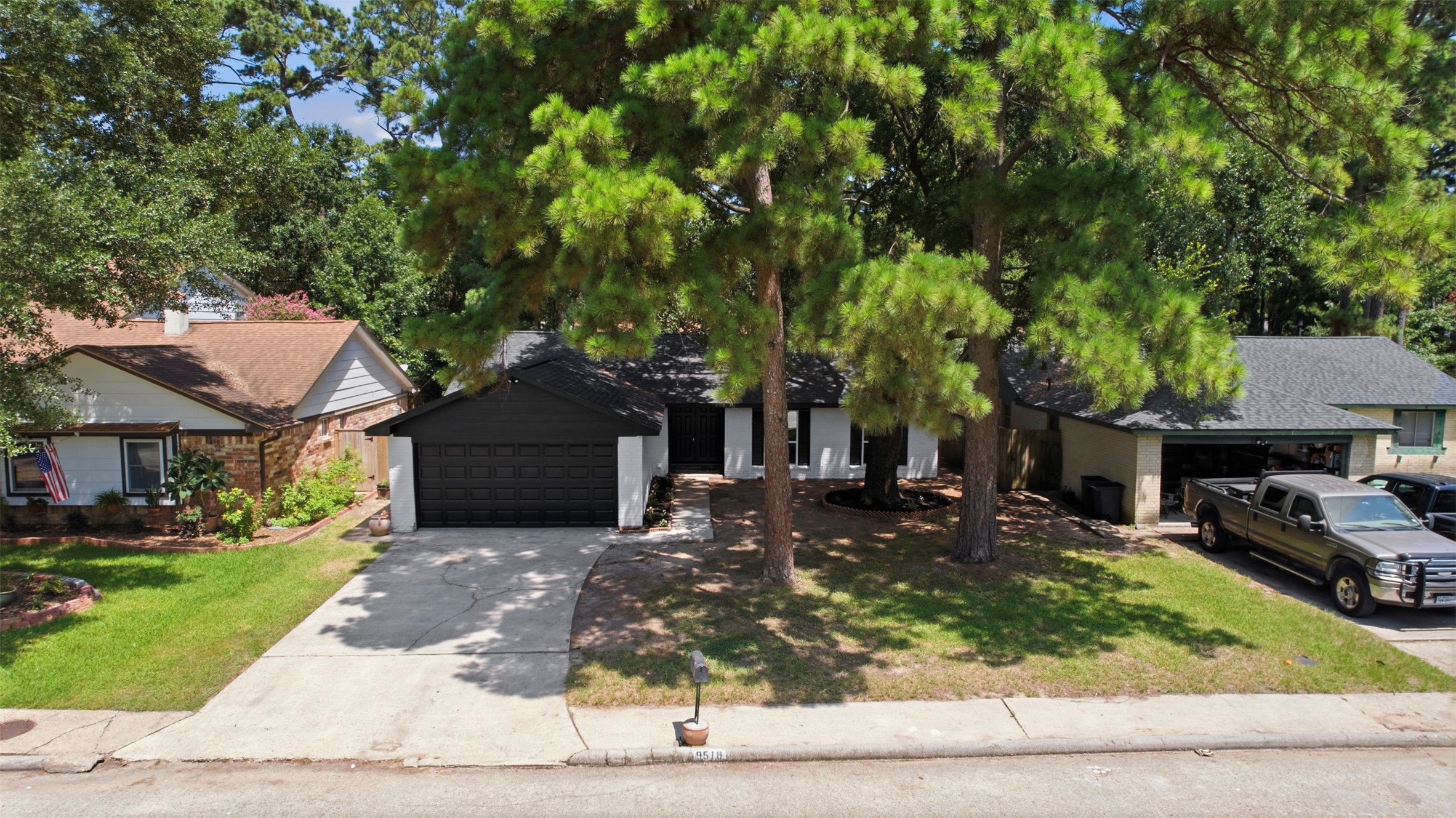 9518 Landry Boulevard Spring, TX 77379 - Photo 29 of 38 Charming single-story home with a dark exterior and a spacious two-car garage. Nestled among mature trees, it offers a serene setting on a quiet street.