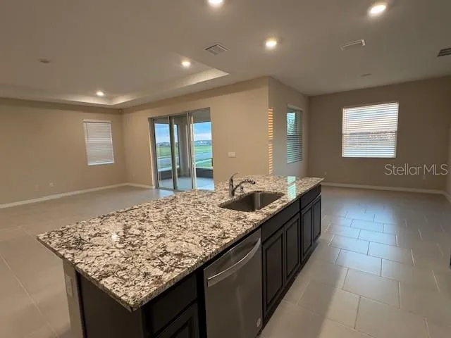 a kitchen with granite countertop wooden cabinets a refrigerator and a sink