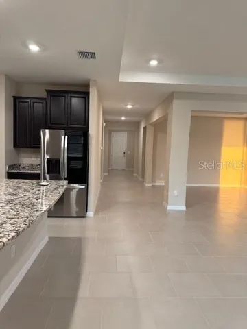 a view of an empty room and kitchen view