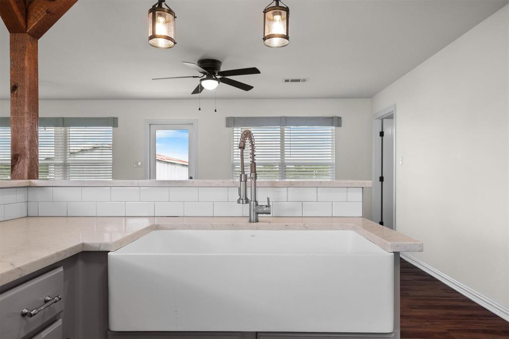 13132 Highway 78 Blue Ridge, TX 75424 - Photo 13 of 35 Farmhouse sink with a spring-style faucet, light-toned countertops, subway tile backsplash, and gray cabinetry with brushed nickel hardware