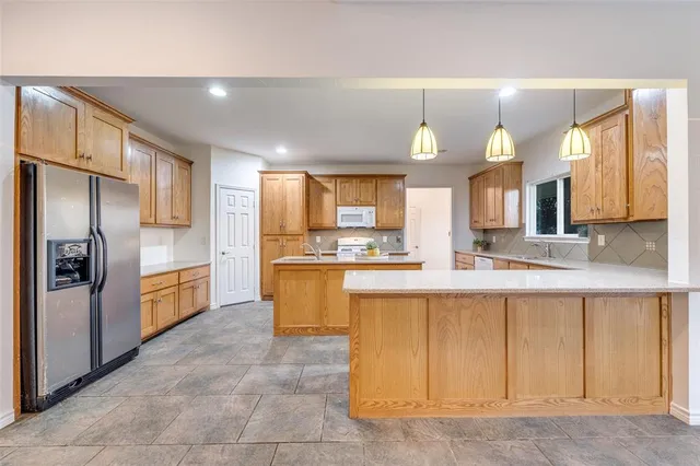 a large kitchen with a large counter top a sink stainless steel appliances and cabinets