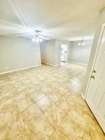 a view of a room with a ceiling fan and carpet