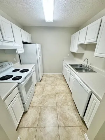 a kitchen with a white stove refrigerator and cabinets
