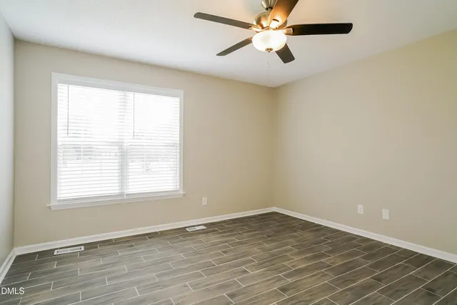 an empty room with a window and a fan