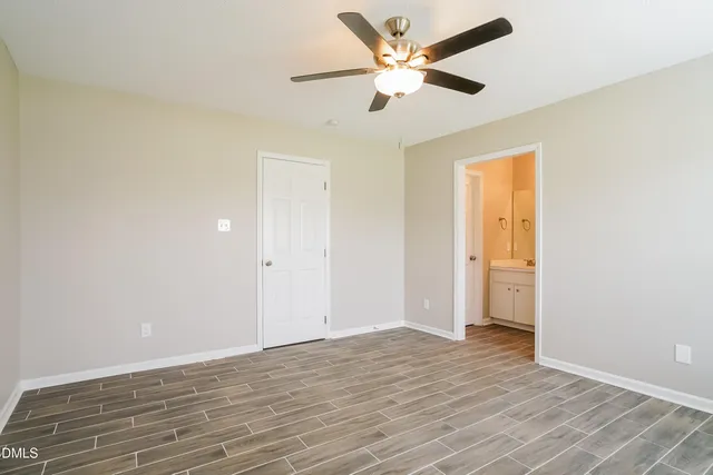 an empty room with wooden floor and a ceiling fan
