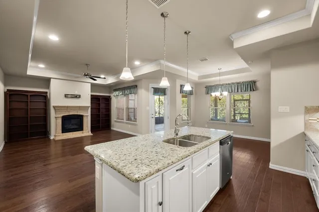 a kitchen with a sink chandelier and wooden floor
