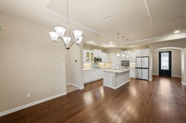 a kitchen with stainless steel appliances granite countertop a stove top oven a sink dishwasher and a fireplace with wooden floor