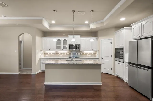 a view of a kitchen with center island stainless steel appliances wooden floor and living room view