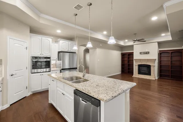 a kitchen with kitchen island granite countertop a stove a sink a center island and wooden floor