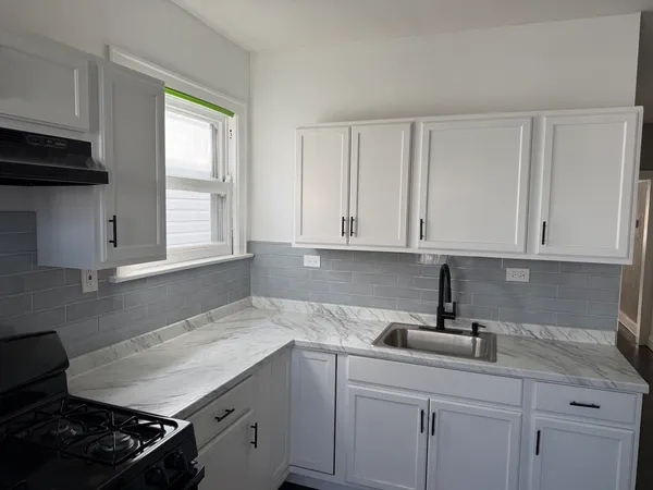 a kitchen with white cabinets and a stove top oven
