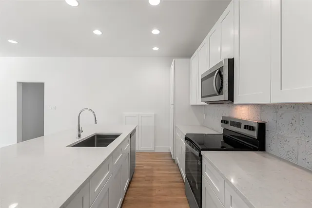 a kitchen with stainless steel appliances a sink a stove top oven a counter space and cabinets