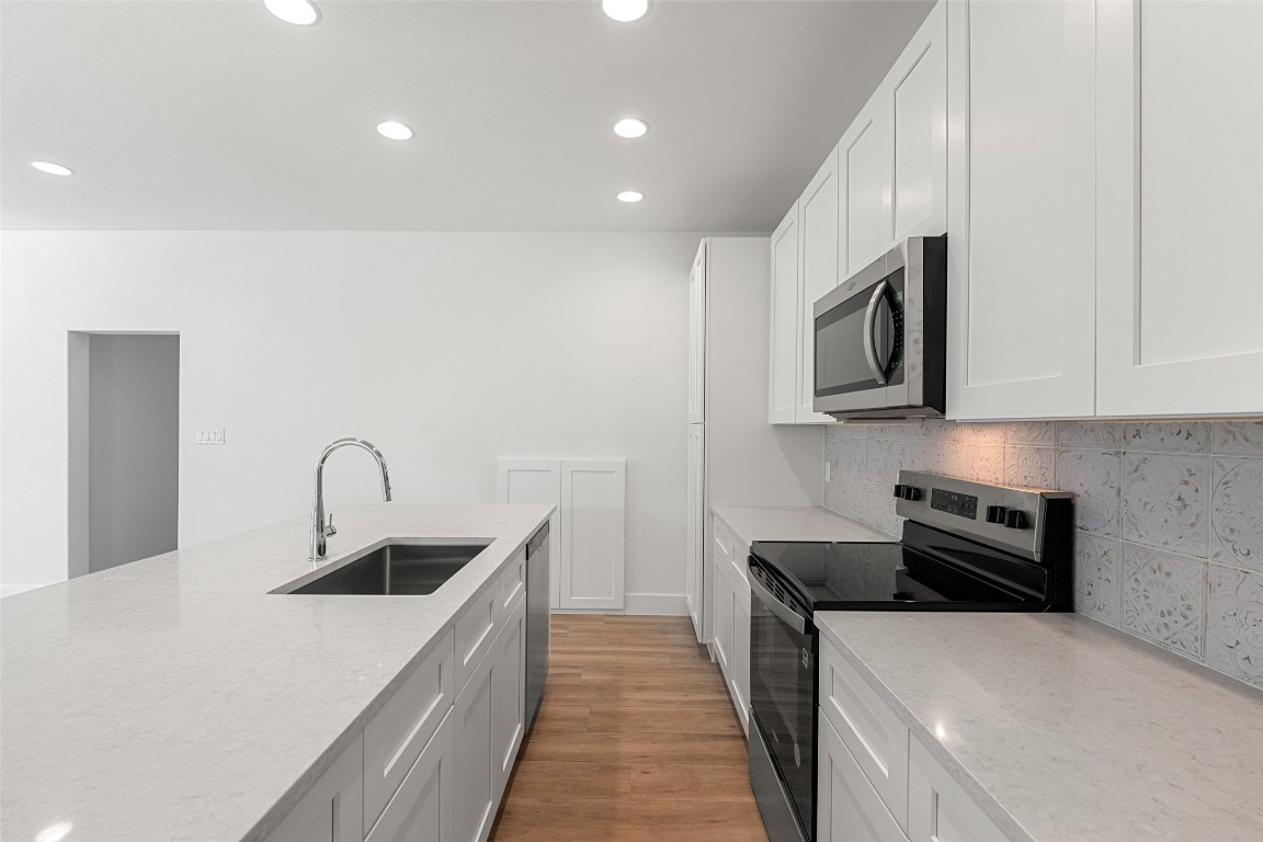 711 Paleface Ranch Road, Unit 3 Spicewood, TX 78669 - Photo 11 of 33 a kitchen with stainless steel appliances a sink a stove top oven a counter space and cabinets