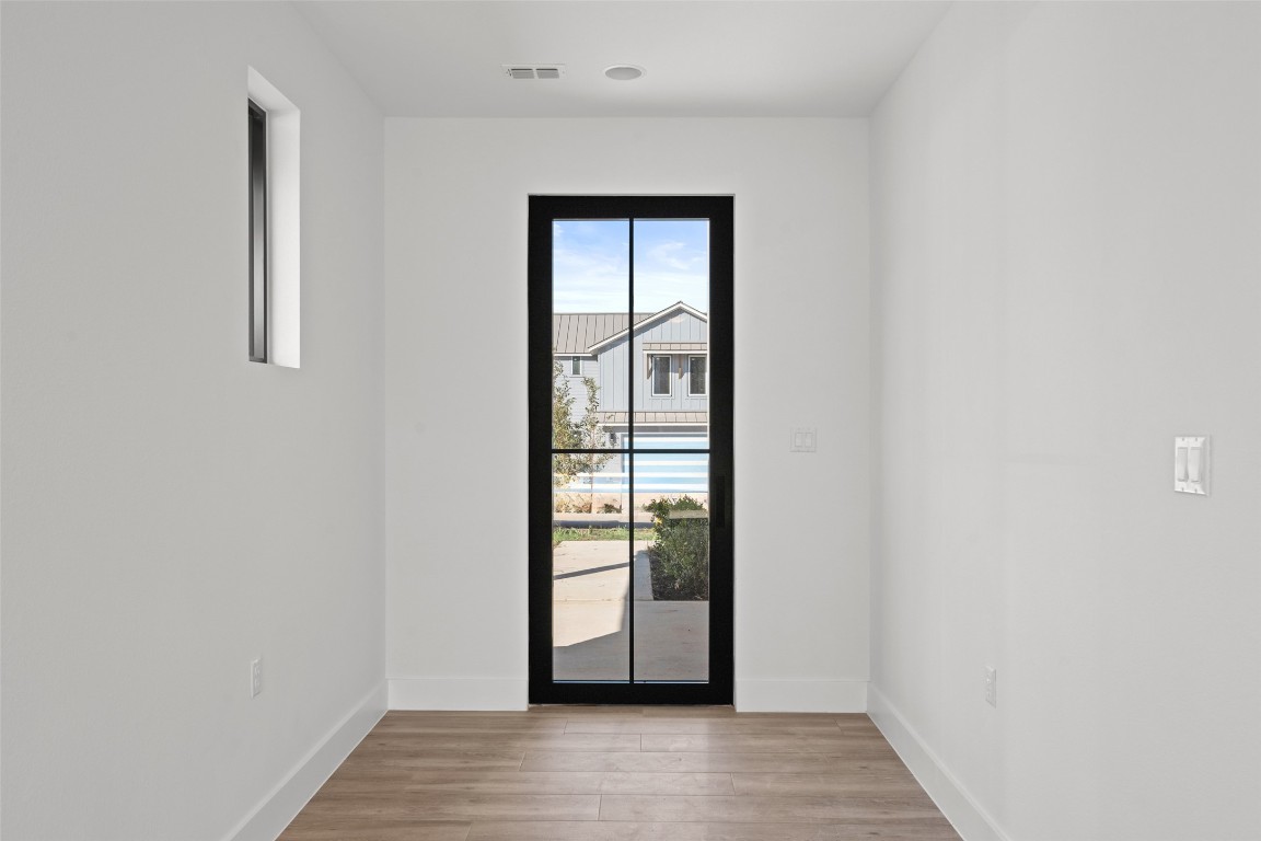 711 Paleface Ranch Road, Unit 3 Spicewood, TX 78669 - Photo 3 of 33 a view of an empty room with wooden floor and a window