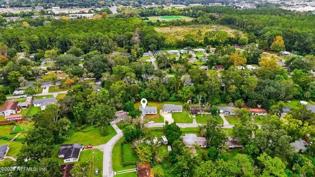 an aerial view of residential houses with outdoor space and trees