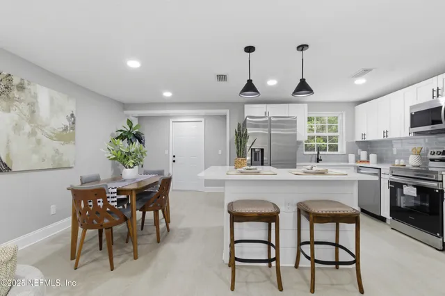 a kitchen with stainless steel appliances a dining table chairs and granite counter tops