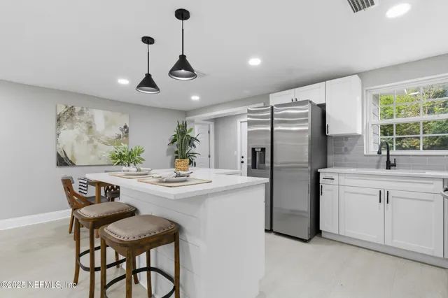 a kitchen with stainless steel appliances a dining table chairs and white cabinets