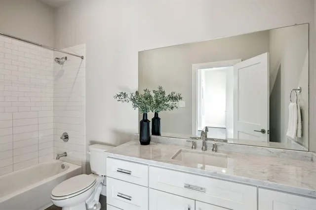 a bathroom with a granite countertop sink a toilet a large mirror a vanity and shower