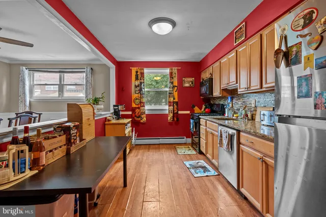 a kitchen with stainless steel appliances granite countertop a stove a refrigerator a dining table and chairs with wooden floor