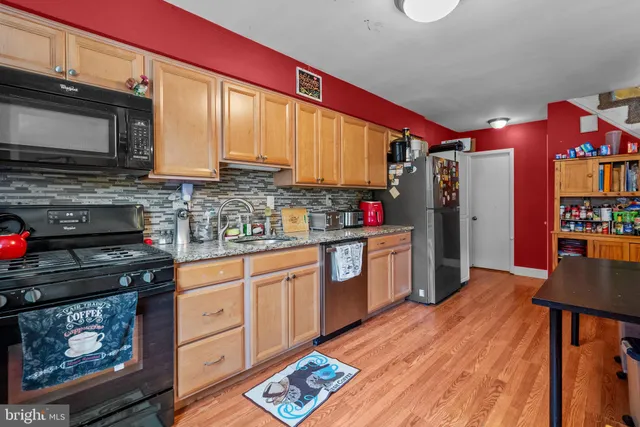 a kitchen with stainless steel appliances a stove top oven a sink dishwasher and cabinets with wooden floor