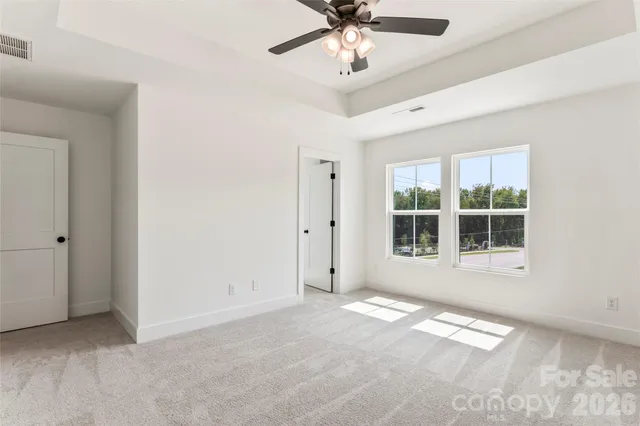 an empty room with a ceiling fan and carpet