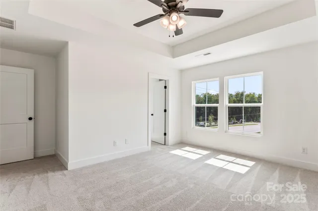 an empty room with a ceiling fan and carpet