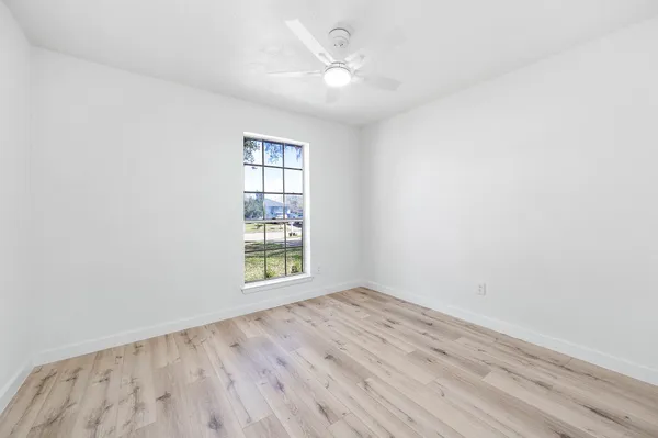 an empty room with a window and a fan