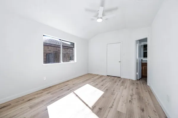 an empty room with wooden floor chandelier fan and windows