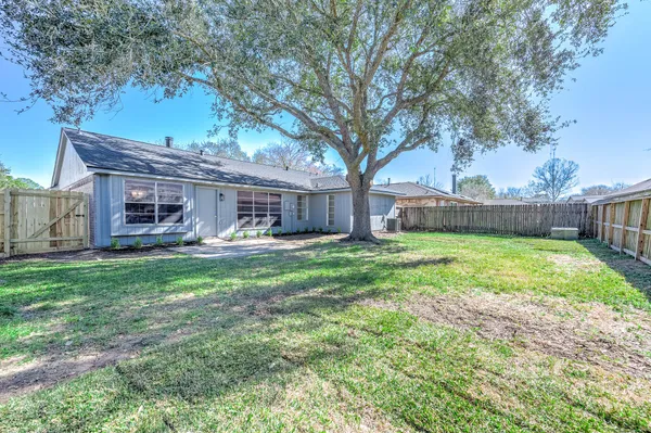 a front view of a house with garden and a large tree