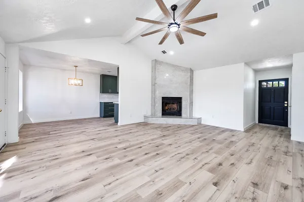 a view of an empty room with a fireplace and a ceiling fan