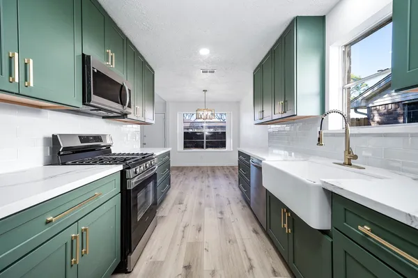 a kitchen with stainless steel appliances granite countertop a stove a sink and a microwave