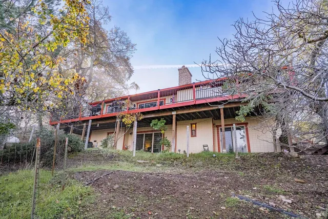 a view of a house with a yard and large trees