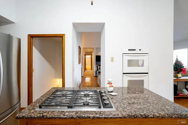 a living room with stainless steel appliances kitchen island granite countertop a refrigerator and stove