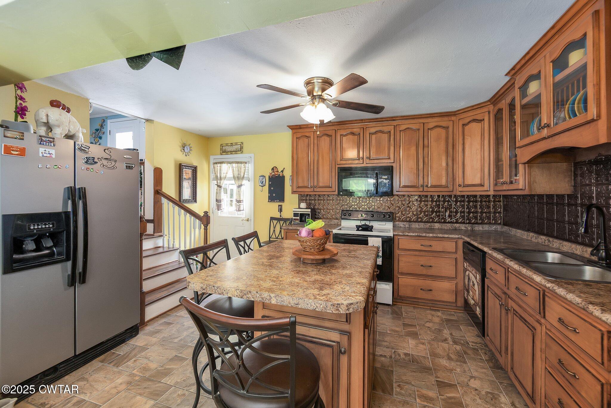 3600 Pine Top Road Toone, TN 38381 - Photo 11 of 39 a kitchen with stainless steel appliances granite countertop a stove a refrigerator a sink a dining table and chairs with wooden floor