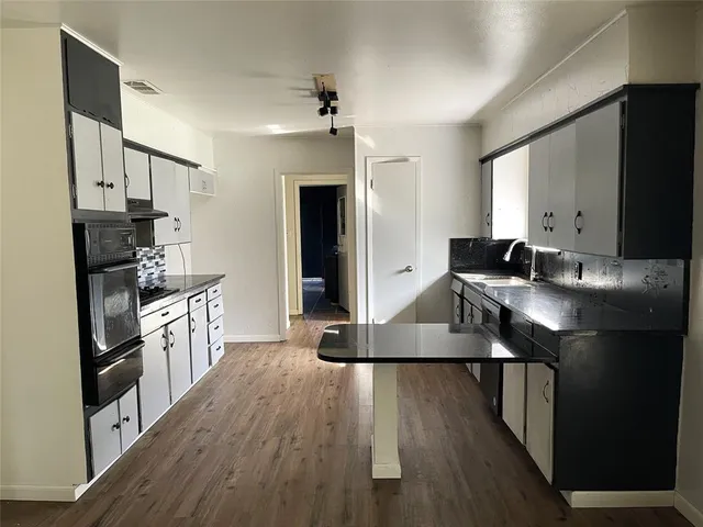a kitchen with kitchen island granite countertop a sink appliances and cabinets