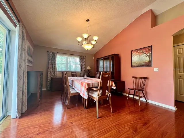 a dining room with wooden floor a chandelier a glass table and chairs