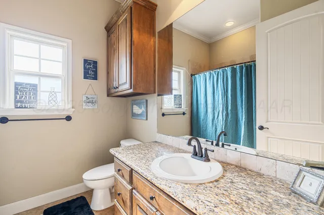 a bathroom with a granite countertop sink toilet and mirror