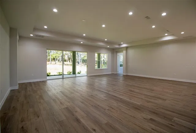a view of a big room with wooden floor and windows